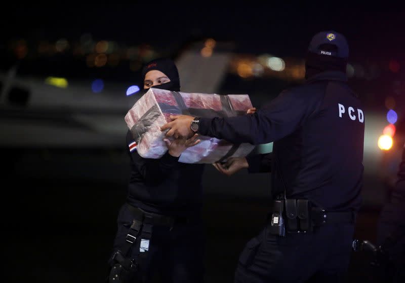 Police officers carry packages containing cocaine seized during an operation in the Caribbean, at the air base of the Ministry of Security in Alajuela