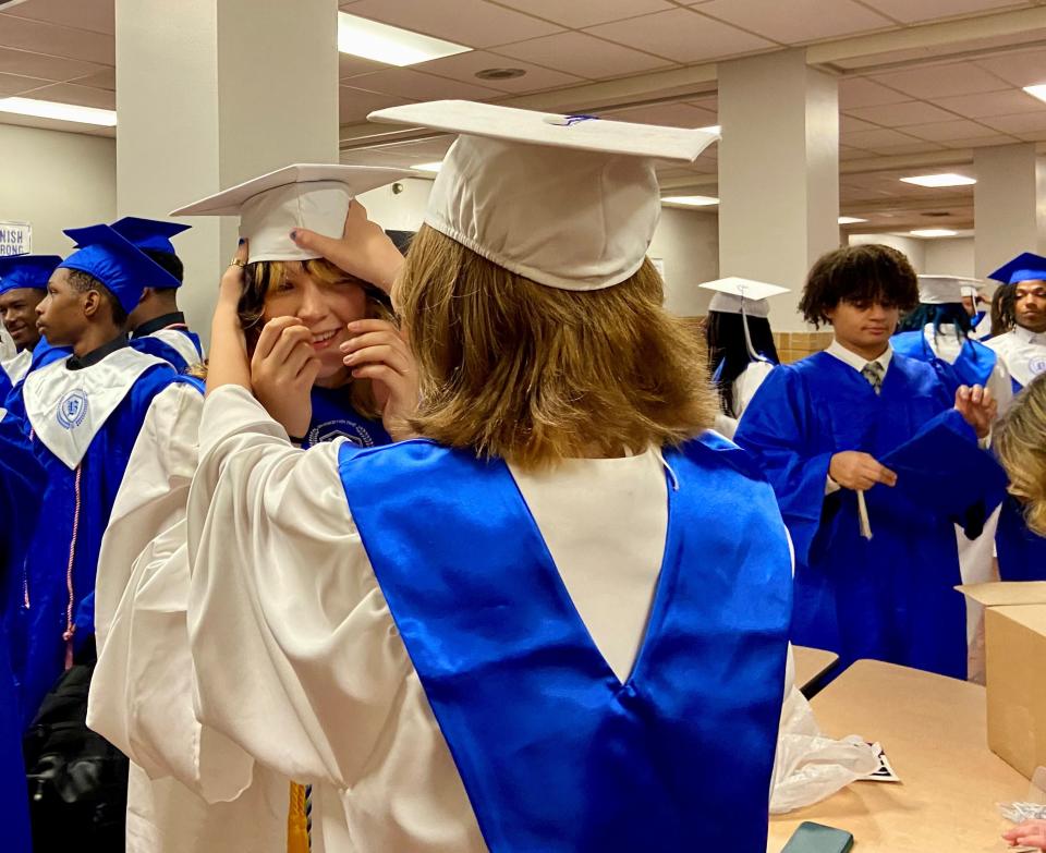 Stella Voorhies laughs as Emily Morris arranges her mortarboard Monday before Bolton High School's commencement ceremony.