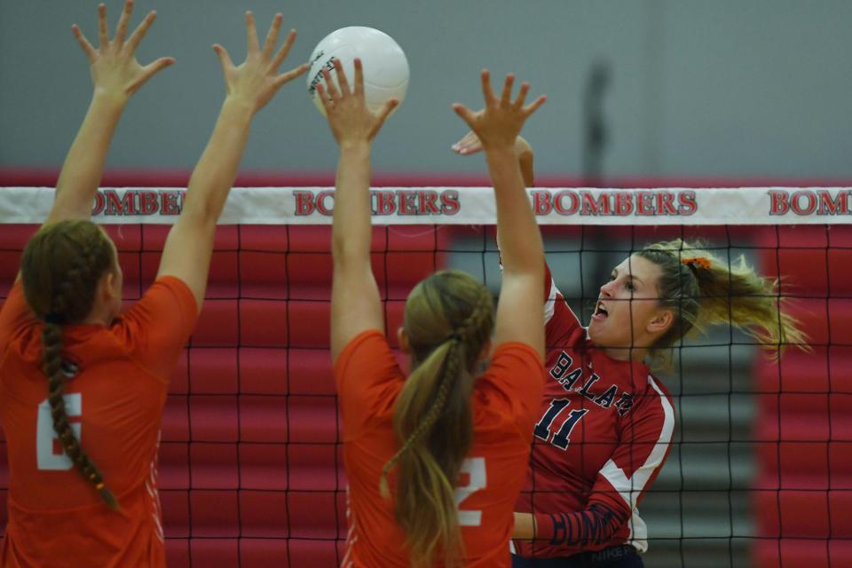 Ballard's Kate MIller (11) spikes the ball over Carroll's Olivia Rowedder (6) and Carroll's Shayne Aschinger (12) during the first set of the Bombers' loss at the Ballard High School gym on Tuesday, Sept. 20, 2022, in Huxley, Iowa.