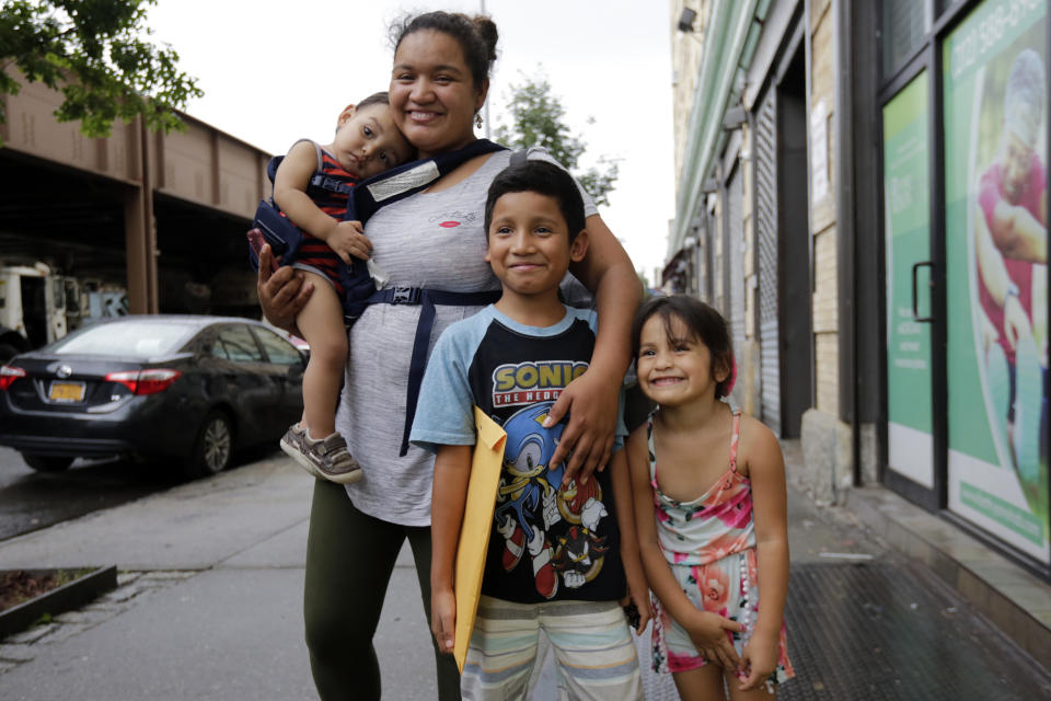 In this Friday, Aug. 3, 2018, photo, Nahun Eduardo Puerto Pineda, then 8, holding envelope, from Honduras, poses for a photo with his mother, Eilyn Carbajal, and two siblings after being reunited with them at the Cayuga Center, in New York. (AP Photo/Richard Drew)