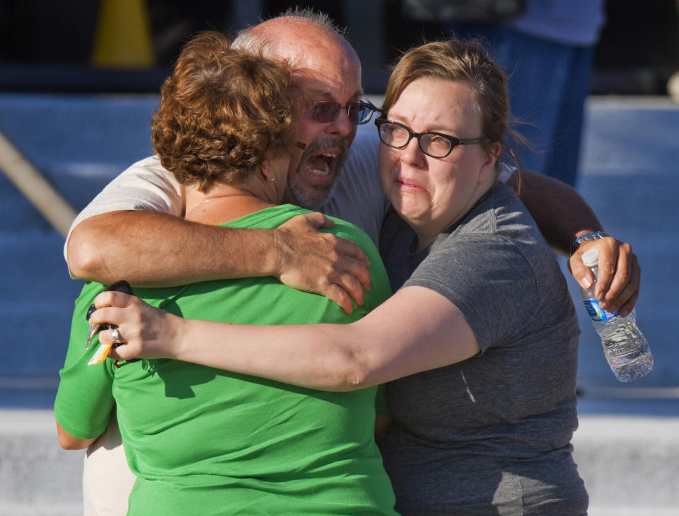 Tom Sullivan, center, embraces family members outside Gateway High School where he had been searching frantically for his son Alex Sullivan, who celebrated his 27th birthday by going to see "The Dark Knight Rises" movie, during which a gunman opened fire on theatergoers, on Friday, July 20, 2012, in Aurora, Colo. Alex was later confirmed to have been killed in the shooting. (AP Photo/Barry Gutierrez)