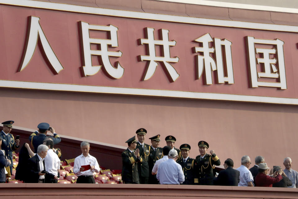 Attendees pose for photos near the words "People's Republic of China" before the start of a parade to mark the 70th anniversary of the founding of the People's Republic of China in Beijing on Tuesday, Oct. 1, 2019. (AP Photo/Ng Han Guan)