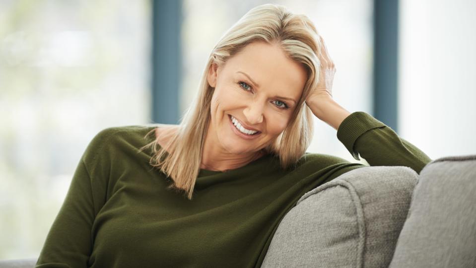 Portrait of a blonde woman relaxing on the sofa at home who has just added highlights with hair makeup