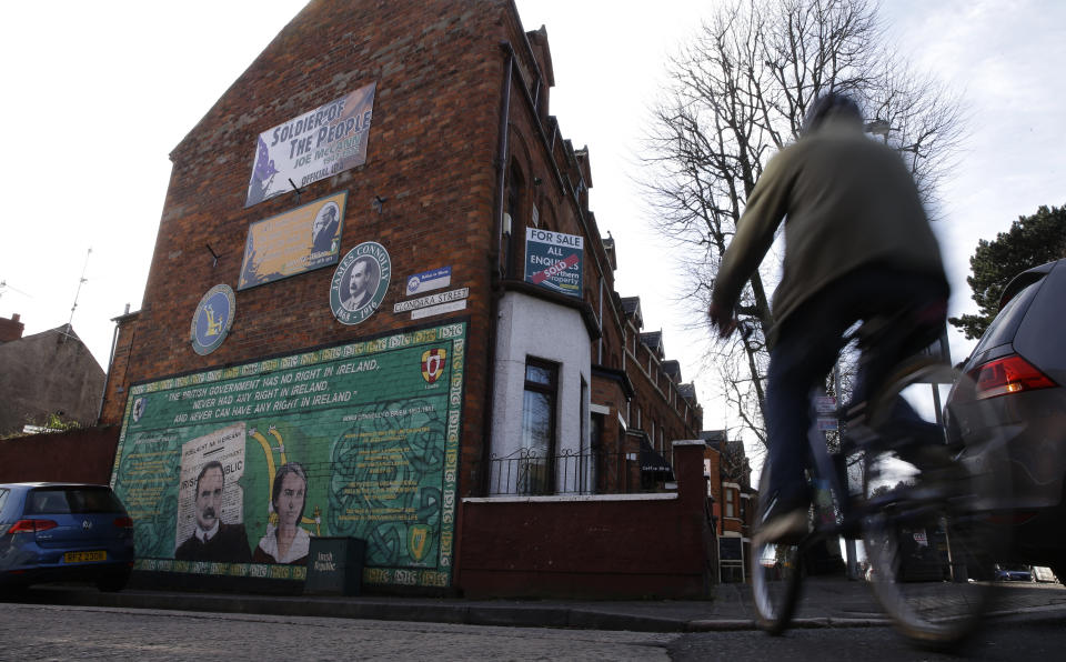 A cyclist passes a mural in the largely Nationalist area of the Fall Road to James Connolly, a leading Irish Republican leader who was executed Dublin in 1916, in Belfast, Northern Ireland, Friday, March 24, 2017. Reminders of the past are everywhere in Belfast _ murals and memorials to those killed in the conflict, along with peace walls that separate predominantly Protestant neighborhoods from mostly Catholic ones _ but there are also new shopping malls and cafes, new tech industries, and lots of tourists. (AP Photo/Alastair Grant)