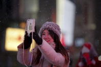 A woman takes a selfie as it begins to snow in Times Square in the Manhattan borough of New York, January 23, 2016. REUTERS/Carlo Allegri