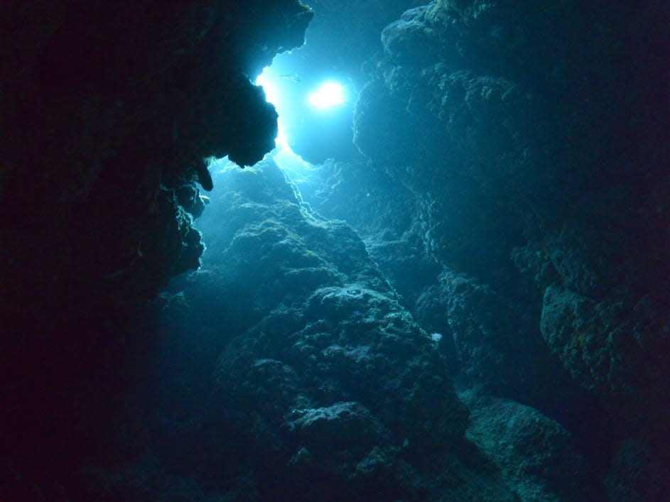 Shot from an underwater cave looking up to the sun at the water's surface.