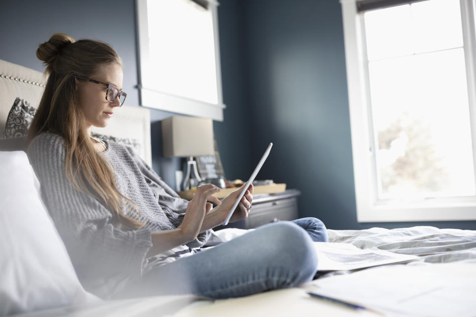 Woman using digital tablet on bed