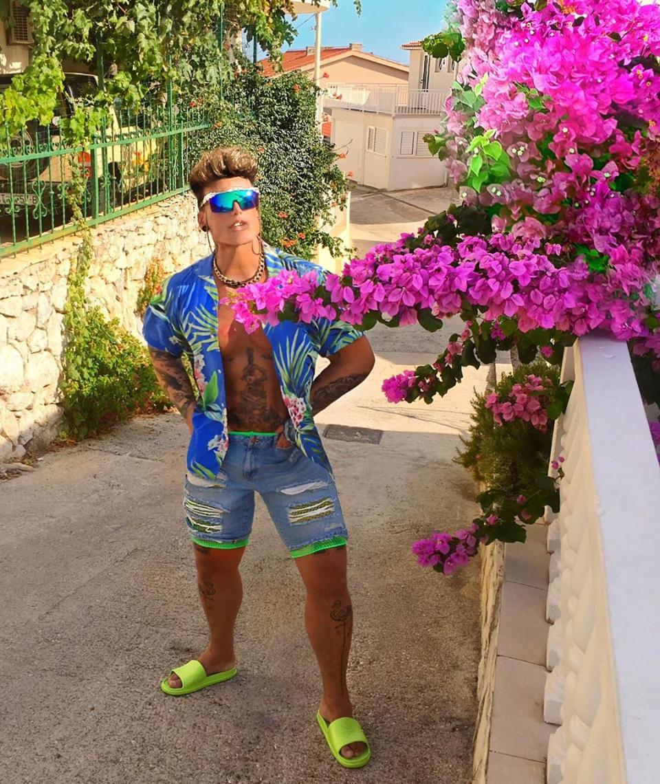A photo of Neven Ciganovic from Zagreb, Croatia, wearing an Hawaiian shirt and denim cut-off shorts with neon green pool slides