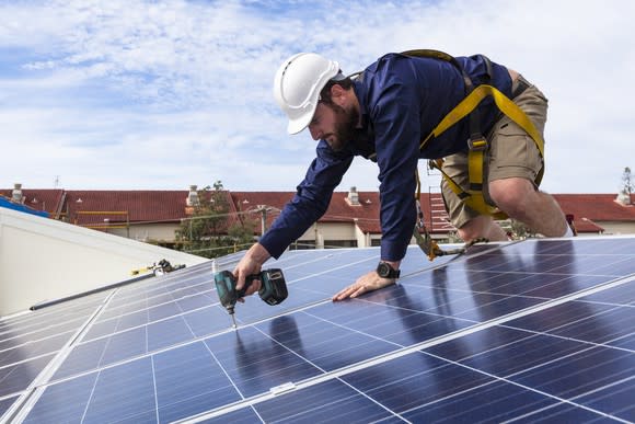 Worker installing solar panels on a roof.