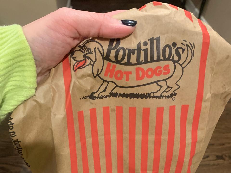 hand holding a portillos hot dogs bag