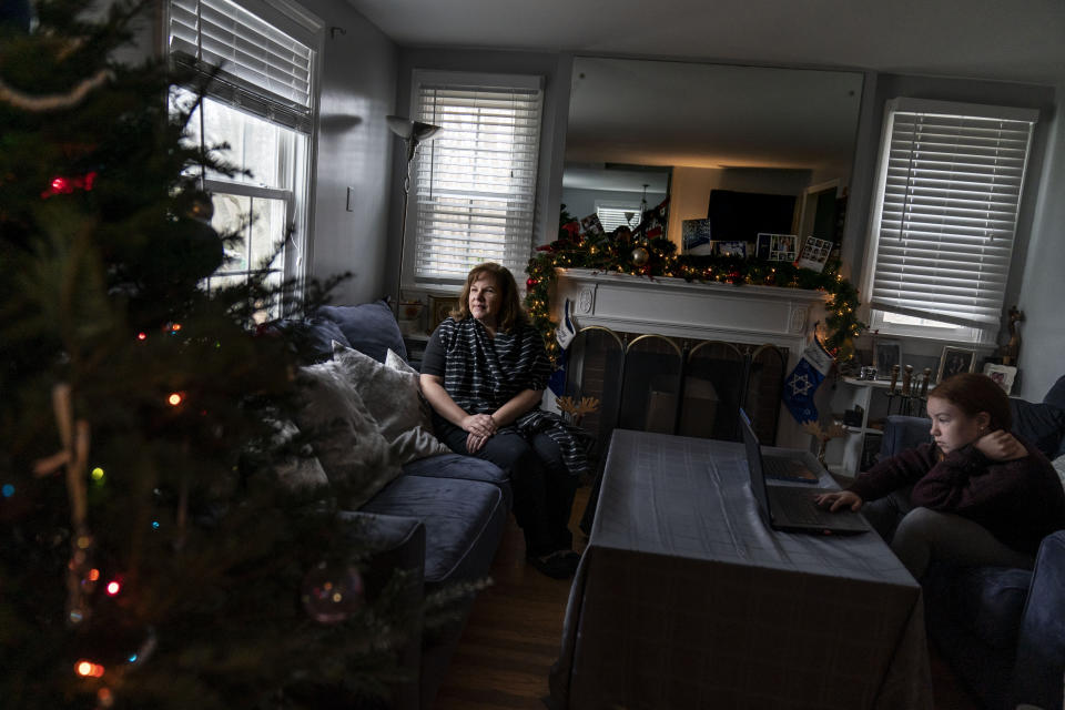 Eileen Carroll, left, sits for a portrait as her daughter, Lily, 11, attends school remotely from their home in Warwick, R.I, Wednesday, Dec. 16, 2020. When Carroll's other daughter tested positive for the coronavirus, state health officials told her to notify anyone her daughter might have been around. Contact tracers, she was told, were simply too overwhelmed to do it. It's the same story across the U.S., as a catastrophic surge in infections has made it difficult or impossible to keep up with the calls considered critical to controlling outbreaks. (AP Photo/David Goldman)