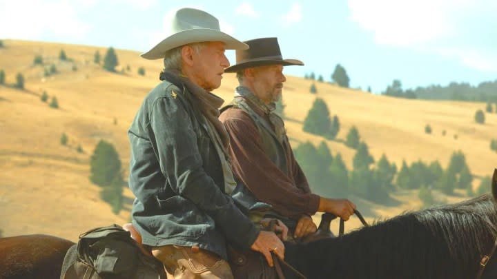 Two cowboys look into the horizon in 1923.