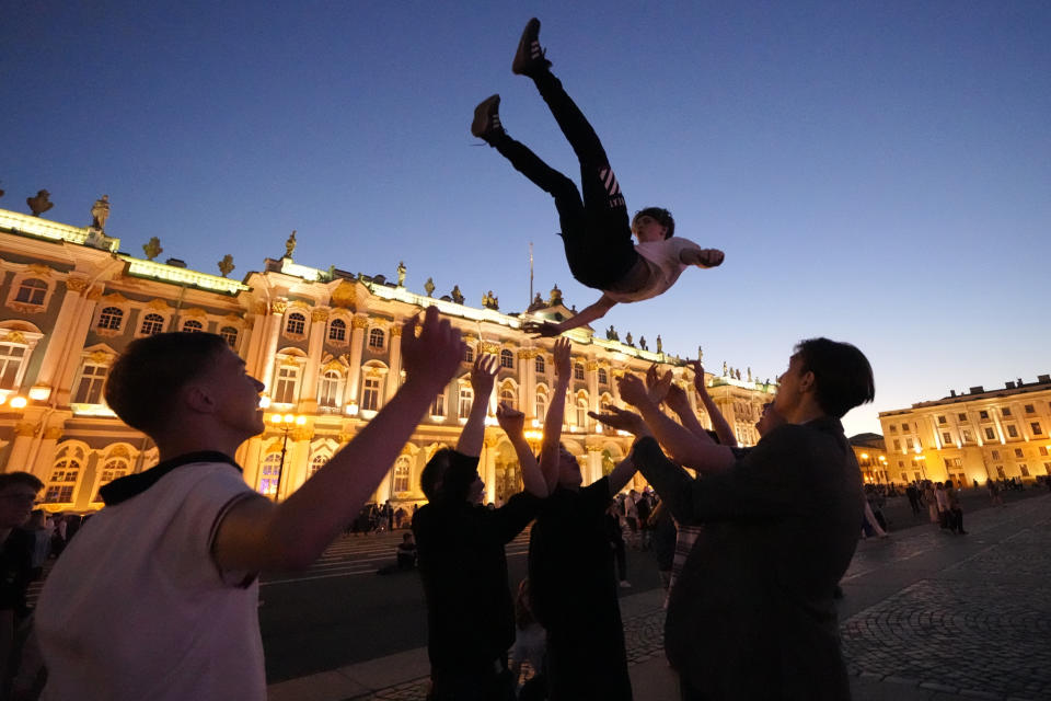 School graduates throw their friend in the air in the Palace Square as they take part the Scarlet Sails festivities marking school graduation in St. Petersburg, Russia, early Saturday, June 25, 2022. (AP Photo/Dmitri Lovetsky)