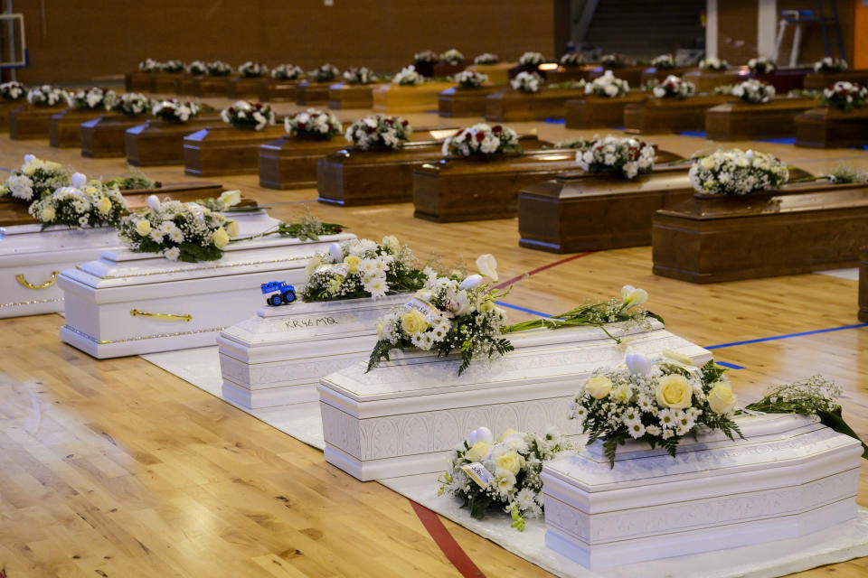 FILE - This Feb. 28, 2023 file photo shows inside the PalaMilone sports center in Crotone, southern Italy, the coffins of the migrants who died after their boat capsized in the early morning of Sunday, Feb. 26, 2023, at a short distance from the shore in Steccato di Cutro, in the Italian southern tip, killing at least 94 people, aligned in a sports center in Crotone, southern Italy. Survivors and family members of the victims are converging in the area for a commemoration on Monday, Feb. 26, 2024, on the first anniversary of the disaster. (AP Photo/Valeria Ferraro)