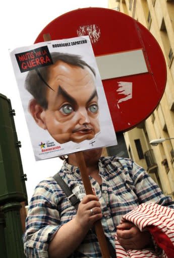 An anti-government demonstrators holds a placard displaying a cartoon depicting Spanish Prime Minister Jose Luis Rodriguez Zapatero during a protest in front of the headquarters of the Spanish Socialist Party (PSOE) in Madrid