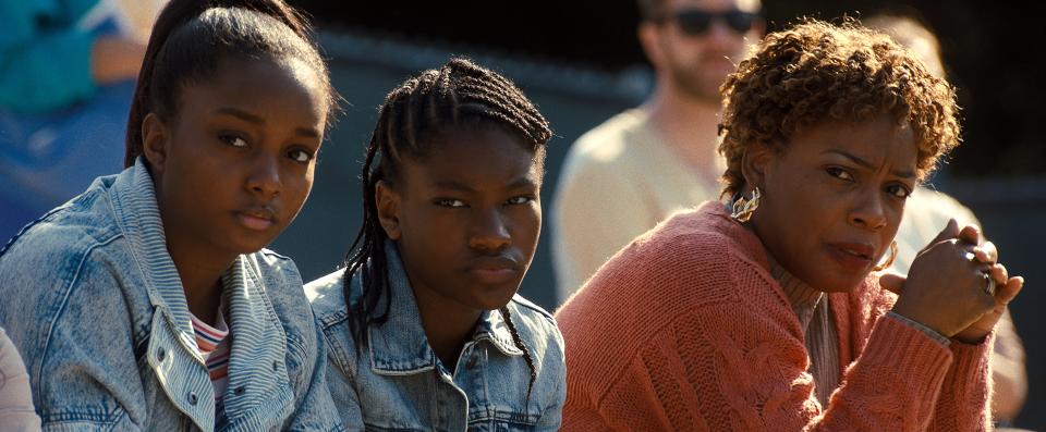 Oracene (Aunjanue Ellis, far right) attends a tennis match with daughters Isha (Daniele Lawson) and Serena (Demi Singleton) in "King Richard."