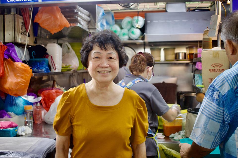 a singaporean woman in front of a hawker stall