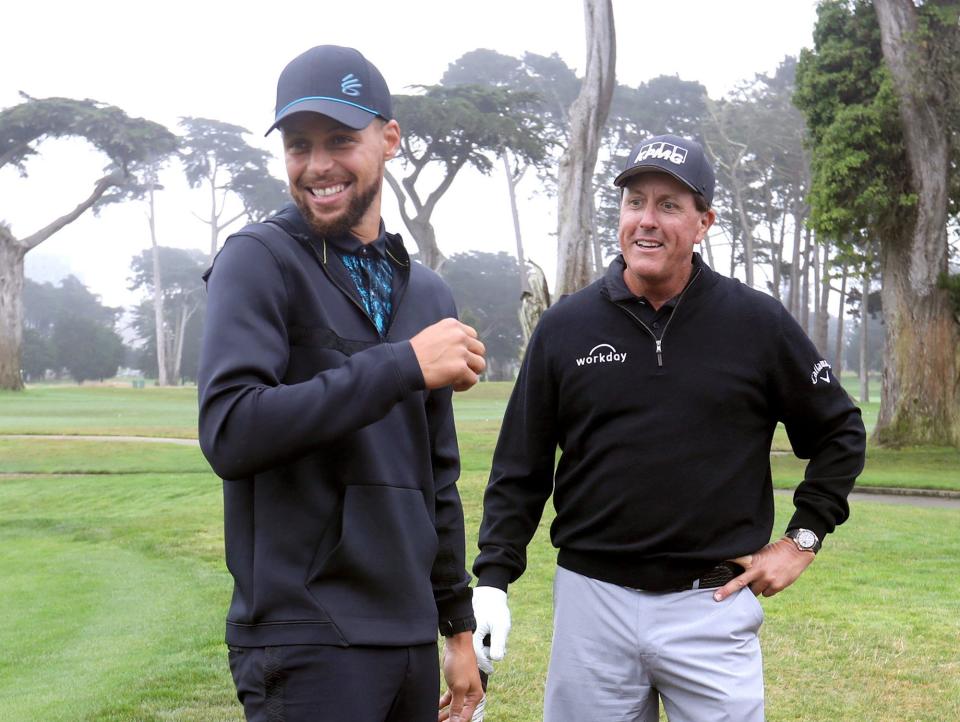 Stephen Curry smiles while talking to Phil Mickelson at a golf tournament.