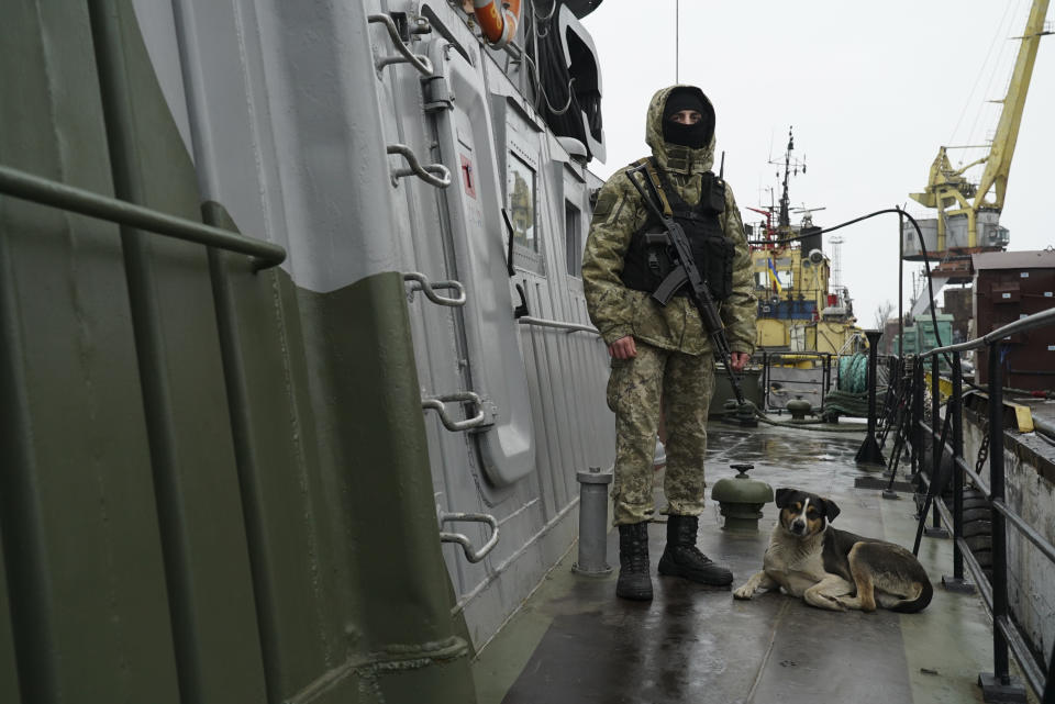 A Ukrainian serviceman stands on board a coast guard ship with his dog in the Sea of Azov port of Mariupol, eastern Ukraine, Monday, Dec. 3, 2018. The Ukrainian military has been on increased readiness as part of martial law introduced in the country in the wake of the Nov. 25, 2018 incident in the Sea of Azov, in which the Russian coast guard fired upon and seized three Ukrainian navy vessels along with their crews. (AP Photo/Evgeniy Maloletka)