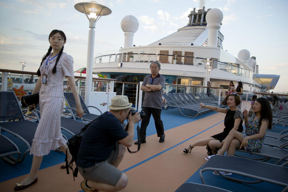 Passengers pose for photos onboard Royal Caribbean's cruise ship the Ovation of the Seas ahead of its inaugural voyage at the International Cruise Terminal in northeastern China's Tianjin Municipality, Friday, June 24, 2016. (AP Photo/Ng Han Guan)