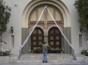 FILE - In this Sunday, April 12, 2020, file photo, a parishioner prays outside the closed doors decorated with Easter lily flowers at the Christ the King Church Roman Catholic Church in Los Angeles. A federal appeals court has denied a Southern California church's request to overturn the state's coronavirus restrictions barring worship services indoors during the coronavirus pandemic. The Sacramento Bee says Friday, Jan. 22, 2021, ruling by the 9th U.S. Circuit Court of Appeals leaves the door open for addressing Gov. Gavin Newsom administration's limits on church attendance if a California county is in a less-restrictive COVID-19 tier. (AP Photo/Damian Dovarganes, File)