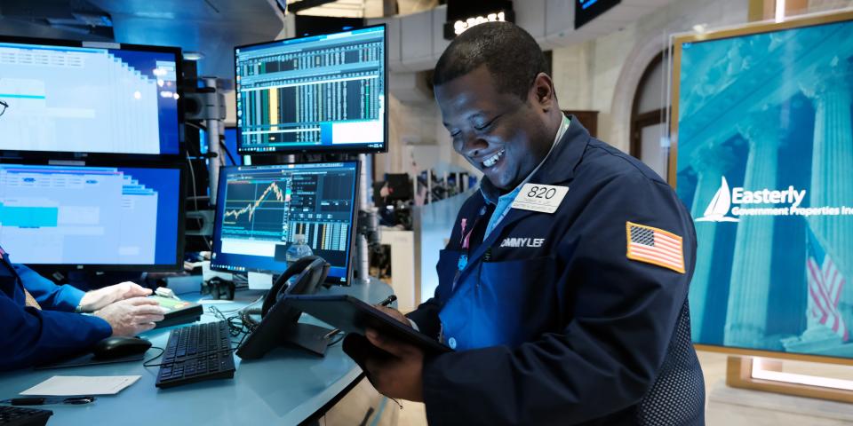 A smiling trader works on the floor of the New York Stock Exchange.