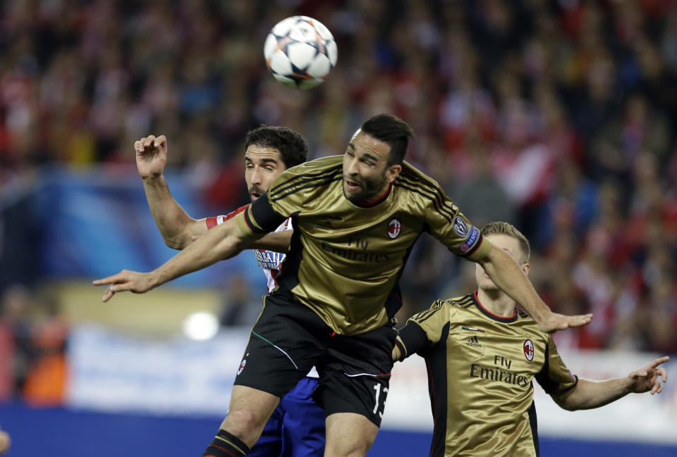 Atletico's Raul Garcia, left, and AC Milan's Adil Rami jump for the ball during a Champions League, round of 16, second leg, soccer match between Atletico Madrid and AC Milan at the Vicente Calderon stadium in Madrid, Tuesday March 11, 2014. (AP Photo/Paul White)