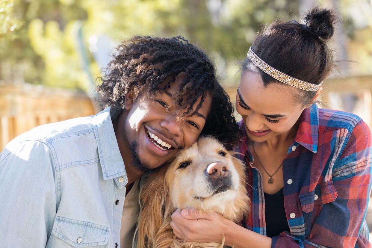 Confident young couple spend time playing with their cute dog.