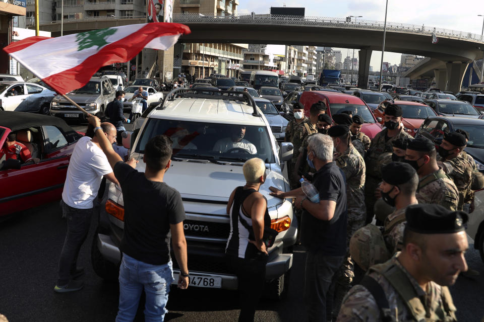 Lebanese army soldiers stand guard as protesters block a main highway, in the town of Jal el-Dib, north of Beirut, Lebanon, Thursday, June 24, 2021. Dozens of angry protesters, angered by deteriorating living conditions and government inaction, partially blocked Beirut's main highway to the capital's only airport, turning trash bin over and setting tires on fire. (AP Photo/Bilal Hussein)