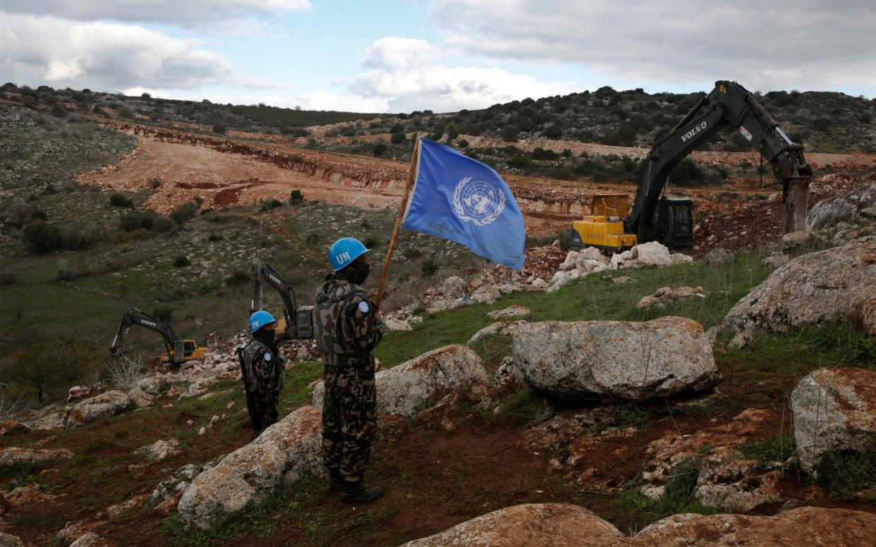 UN peacekeepers look on as Israeli troops destroy a tunnel - AP