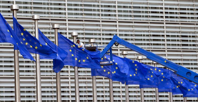 A worker on a lift adjusts the EU flags in front of EU headquarters in Brussels, June 2016