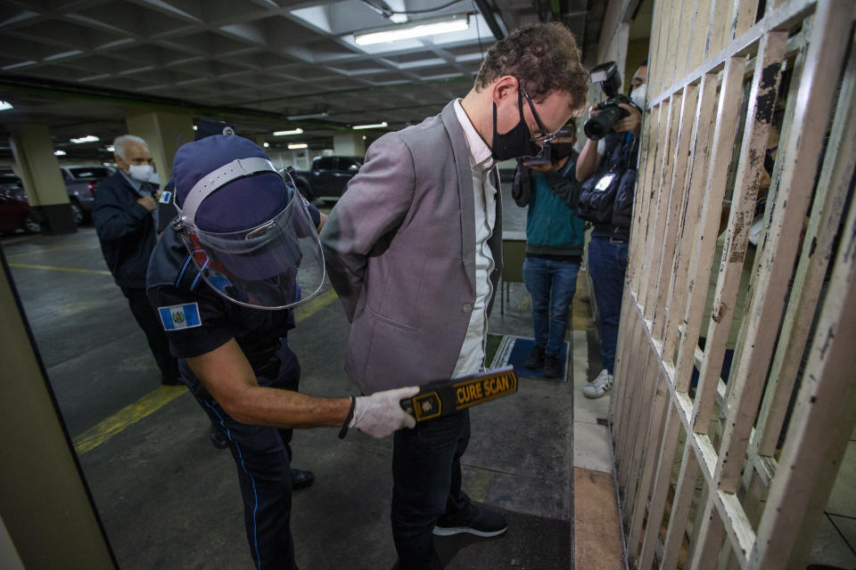 The son of former Panamanian President Ricardo Martinelli, Luis Enrique Martinelli Linares, is frisked by an officer before a hearing at the judicial court building in Guatemala City, Tuesday, July 7, 2020. Luis Enrique and his brother Ricardo were detained Monday on an international warrant from Interpol on charges of conspiracy to commit money laundering. (AP Photo/Moises Castillo)