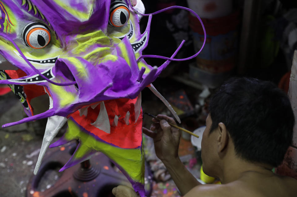 Robert Sicat paints a Dragon's head for a client outside their creekside house at Manila's Chinatown, Binondo, Philippines on Feb. 3, 2021. The Dragon and Lion dancers won't be performing this year after the Manila city government banned the dragon dance, street parties, stage shows or any other similar activities during celebrations for Chinese New Year due to COVID-19 restrictions leaving several businesses without income as the country grapples to start vaccination this month. (AP Photo/Aaron Favila)