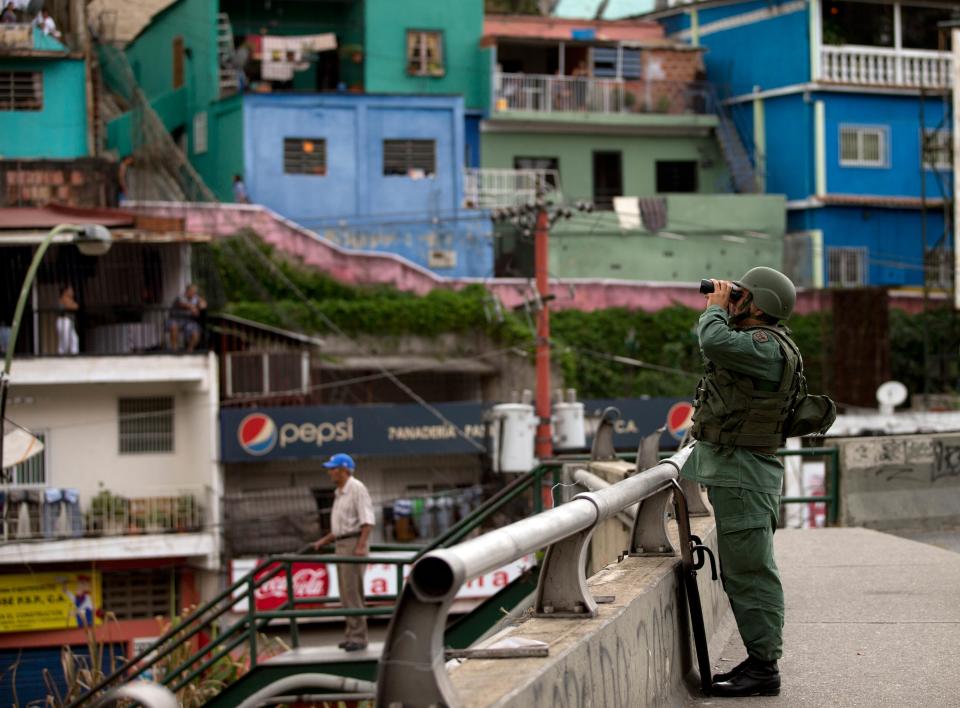 A Bolivarian National Guard soldier looks for demonstrators with binocular during clashes at an anti-government protest in Caracas, Venezuela, Saturday, April 26, 2014. Student organizers at the last minute decided against marching downtown to avoid a confrontation with security forces in the government-controlled district. Instead they concentrated in the wealthier, eastern neighborhoods that have been the hotbed of unrest since February. (AP Photo/Fernando Llano)