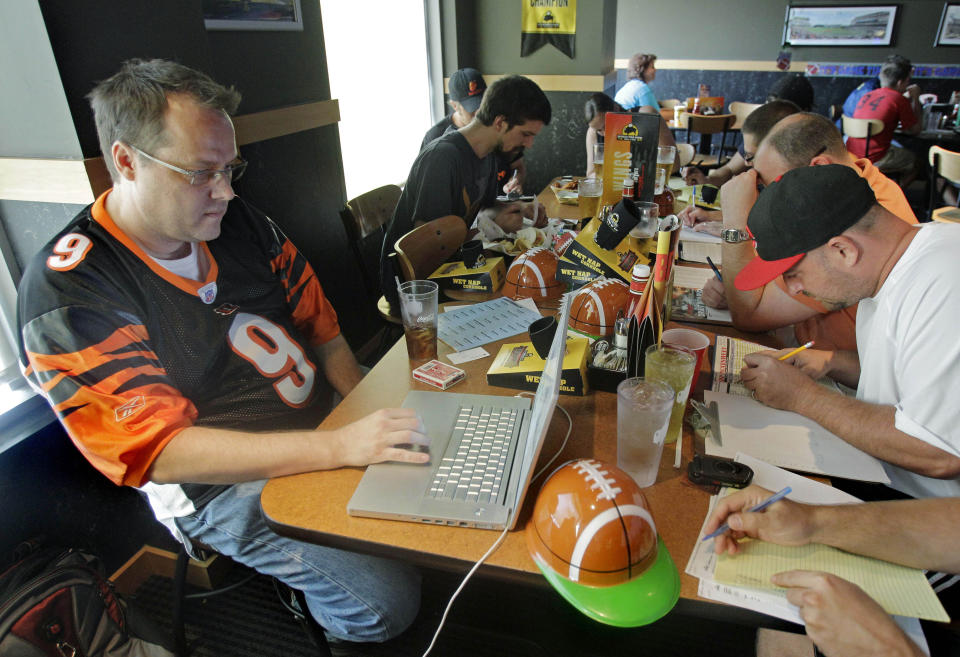 FILE - This Aug. 30, 2010, file photo shows Brian Sherman, left, using his laptop to record moves in his team's fantasy football draft, at a Buffalo Wild Wings restaurant in Cincinnati. From 2007 to 2017, the number of people playing fantasy football more than tripled, from 13.8 million to 42.7 million, according to the Fantasy Sports & Gaming Association. This past Sunday, ESPN’s fantasy app drew 8.3 million unique users _ its biggest day ever _ according to ESPN and Adobe Analytics (AP Photo/Al Behrman, File)