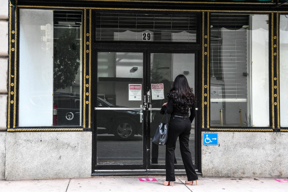A woman reads the sign displayed at a closed business shop in Miami on January 12, 2022. (Photo by CHANDAN KHANNA/AFP)