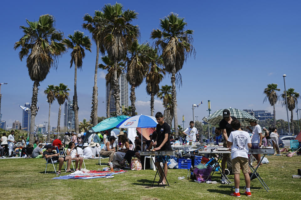 People prepare their food on a grill as they spend the day on a park during Israel's Independence Day celebrations in Tel Aviv, Tuesday, May 14, 2024. Israelis are marking 76 years since Israel's creation. (AP Photo/Ohad Zwigenberg).