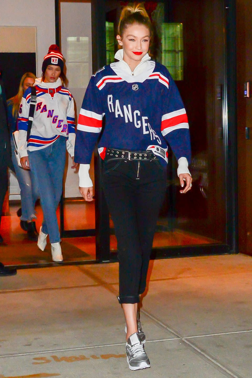 <p>In a Rangers quarter zip, grommet belt, cropped jeans, and silver sneakers while heading to a New York Rangers hockey game with Bella Hadid, who wears a team hoodie, jeans, white boots, and a beanie.</p>