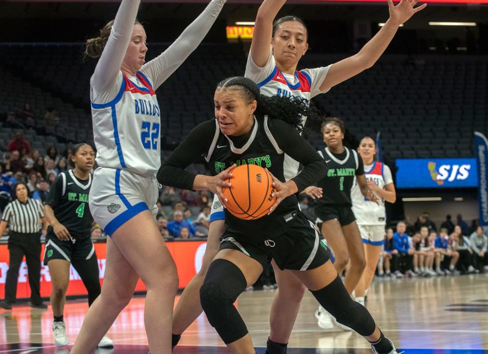 St. Mary's Jordan Lee, center, drives to the hoop between Folsom's Dixie Mclanahan, left, and Kamryn Mafua during the Sac-Joaquin Section girls basketball championship game at Golden One Center in Sacramento on Feb. 21. 2024. St. Mary's won 57-51.