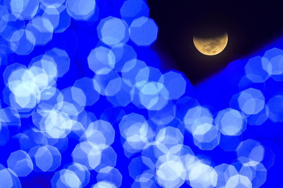 The earth's shadow starts to cover the moon during a lunar eclipse, at a public square in Caracas, Venezuela.