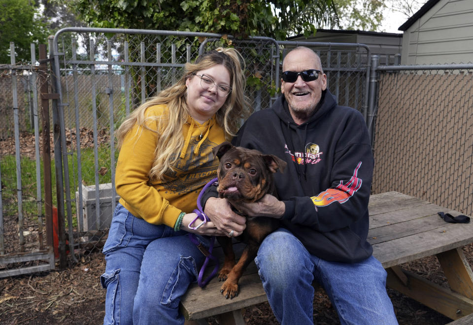 People pose with a dog they decided to adopt at Oakland Animal Services on Thursday, April 4, 2024, in Oakland, Calif. The city animal shelter has seen a surge in pets surrendered by tenants who can't find rentals that allow pets. A California bill aims to make it easier for pet owners to find rental housing. (AP Photo/Terry Chea)