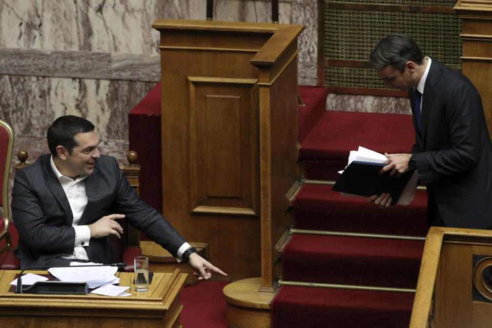 New Democracy party leader Kyriakos Mitsotakis, right, leaves after finishing his speech as Greek Prime Minister Alexis Tsipras, left, points to his dropped notes during a parliamentary session in Athens, on Tuesday, Jan. 15, 2019. Greece's prime minister is defending his deal to normalize relations with neighboring Macedonia ahead of a confidence vote in parliament after his governing coalition collapsed over the agreement. (AP Photo/Petros Giannakouris)