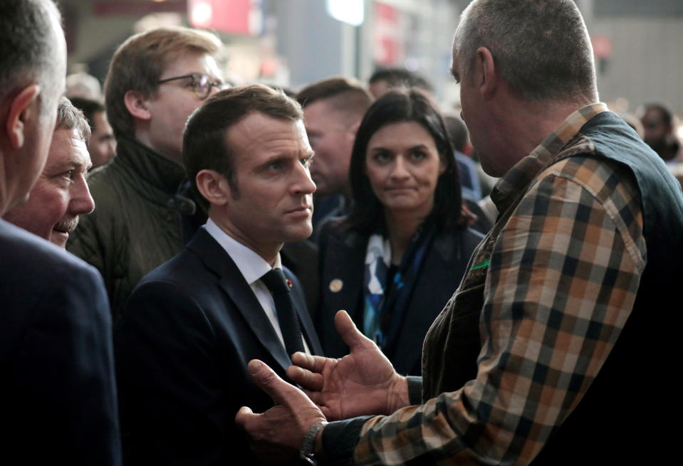 French President Emmanuel Macron, center, meets with exhibitors as he visits the 56th International Agriculture Fair at the Porte de Versailles exhibition center in Paris, France, Saturday, Feb. 23, 2019. Macron pledged to protect European farming standards and culinary traditions threatened by aggressive foreign trade practices that see food as a "product like any other." (Ludovic Marin/Pool Photo via AP)