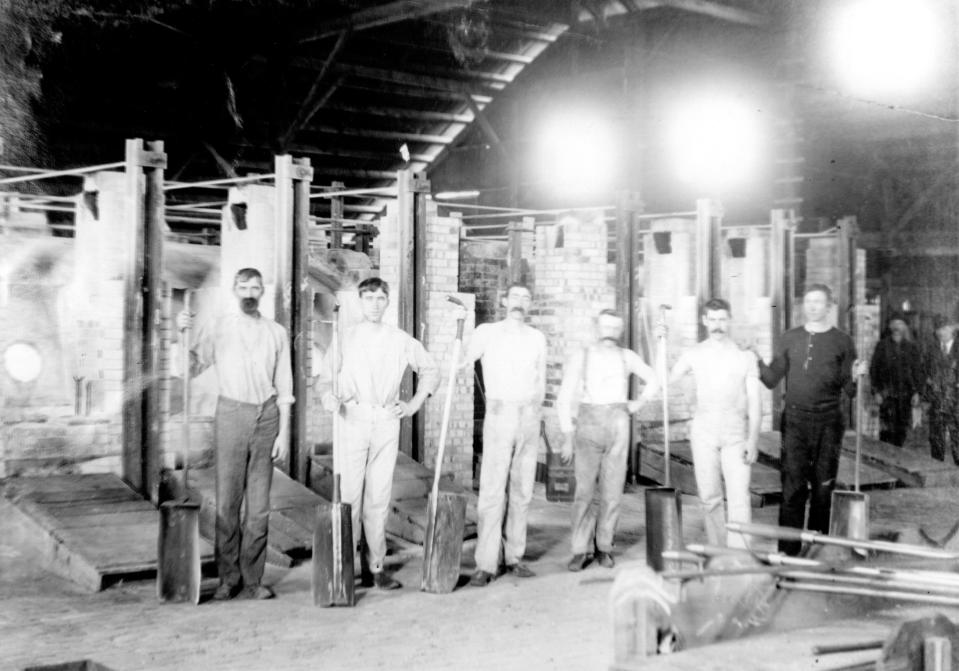 Workers stand in front of their work stations inside the Cole Glass Factory in this undated photograph from the Historical Collection of the Fairfield County District Library.