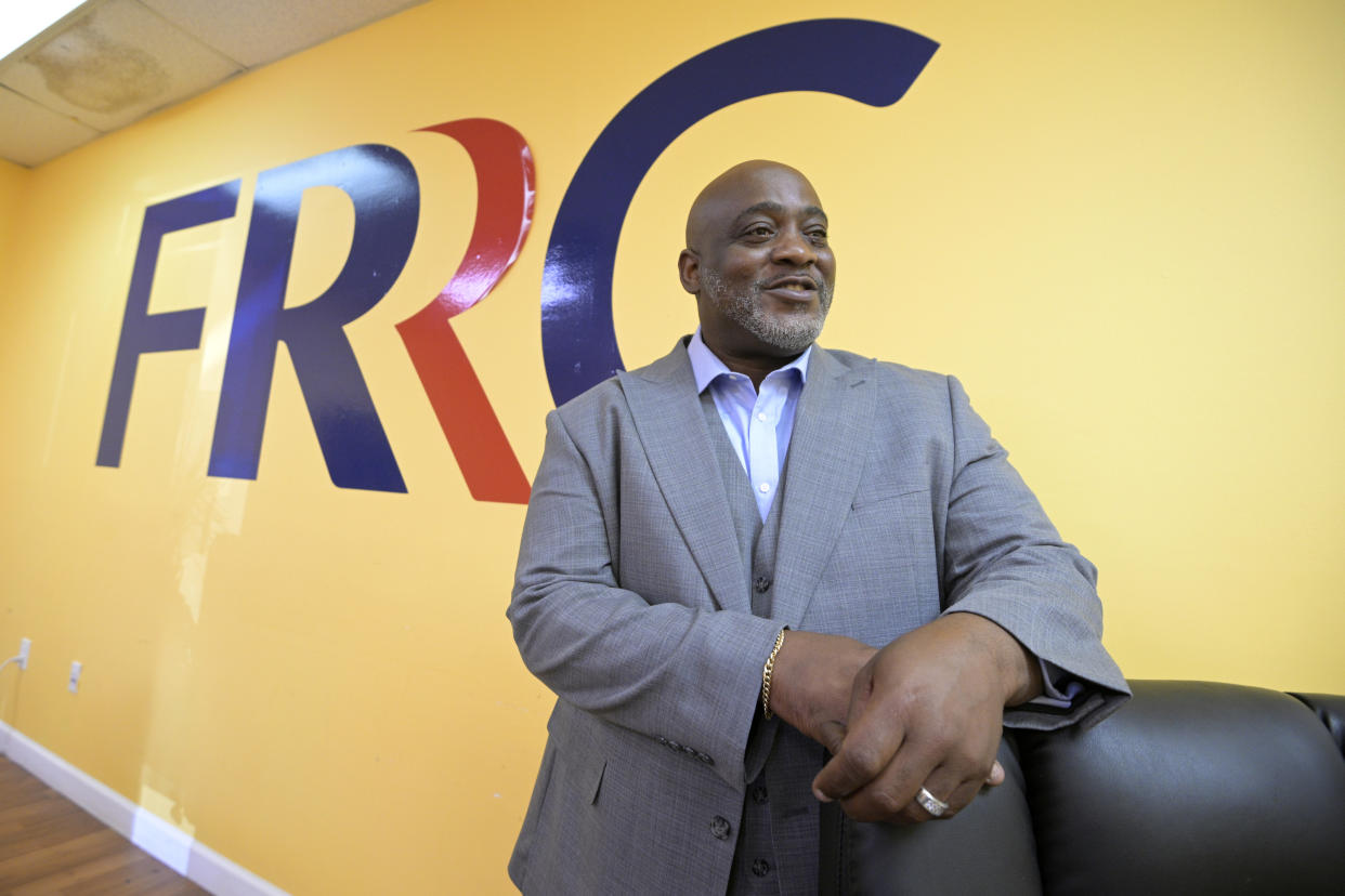 Desmond Meade in front of a wall painted with the FRRC logo.