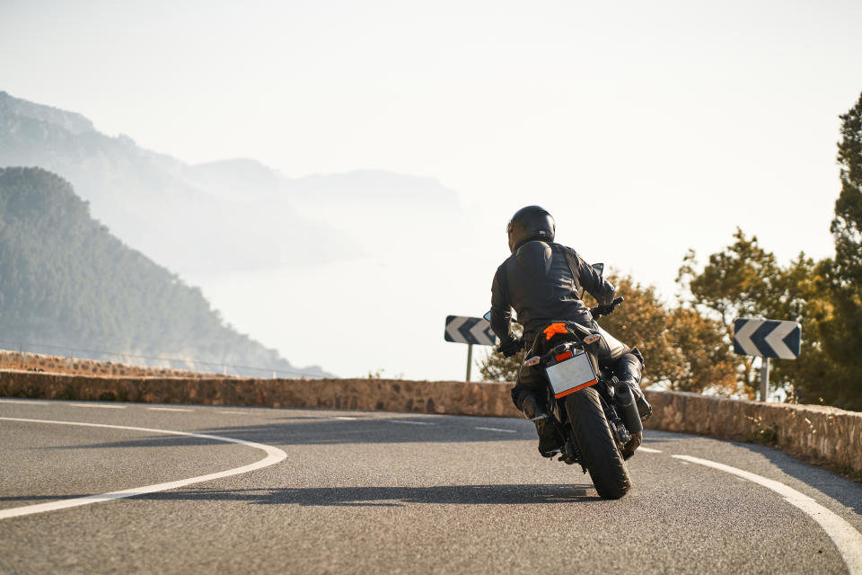 Motorcyclist riding on a curvy mountain road with arrow signs