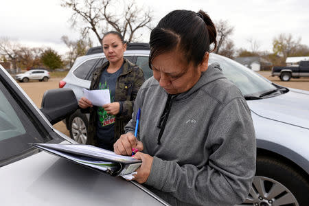 Voting canvasser Desiree McArdel (L) helping Sherri Two Horses update her tribal ID card in order to vote in the 2018 mid-term elections on the Standing Rock Reservation in Fort Yates, North Dakota, U.S. October 26, 2018. REUTERS/Dan Koeck