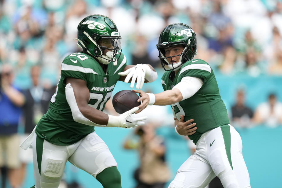 New York Jets quarterback Zach Wilson (2) hands the ball to running back Breece Hall (20) during the first half of an NFL football game against the Miami Dolphins, Sunday, Dec. 17, 2023, in Miami Gardens, Fla. (AP Photo/Rebecca Blackwell)