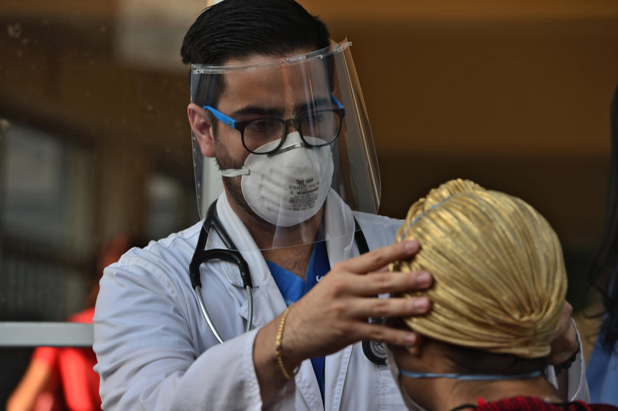 A medical doctor wears a face mask and shield as he examines a patient with symptoms of the new coronavirus in Tegucigalpa, on April 6, 2020. - The Honduran National Risk System (SINAGER) confirmed 30new cases of COVID-19, reaching a total of 298 cases in the Central American nation. (Photo by ORLANDO SIERRA / AFP) (Photo by ORLANDO SIERRA/AFP via Getty Images)