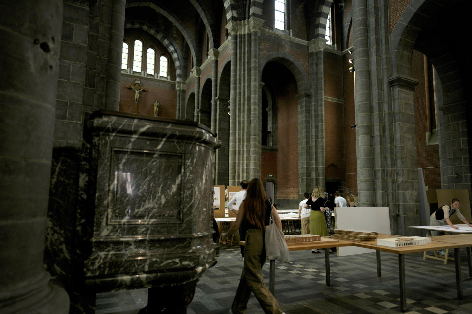 A woman walks by an art installation being set up at the Sacred Heart church in Mechelen, Beligum, Monday, June 19, 2023. Across Europe, the continent that nurtured Christianity for most of two millennia, many churches, convents, beguinages and chapels stand empty as faith and church attendance have dwindled over the past half century. Many are now been repurposed to preserve their historical and architectural relevance, while others have opened up to non-religious activities to expand their use. (AP Photo/Virginia Mayo)